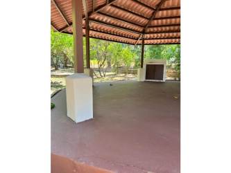 Rustic covered patio with tiled roof and outdoor fireplace at Punta Barco beach property