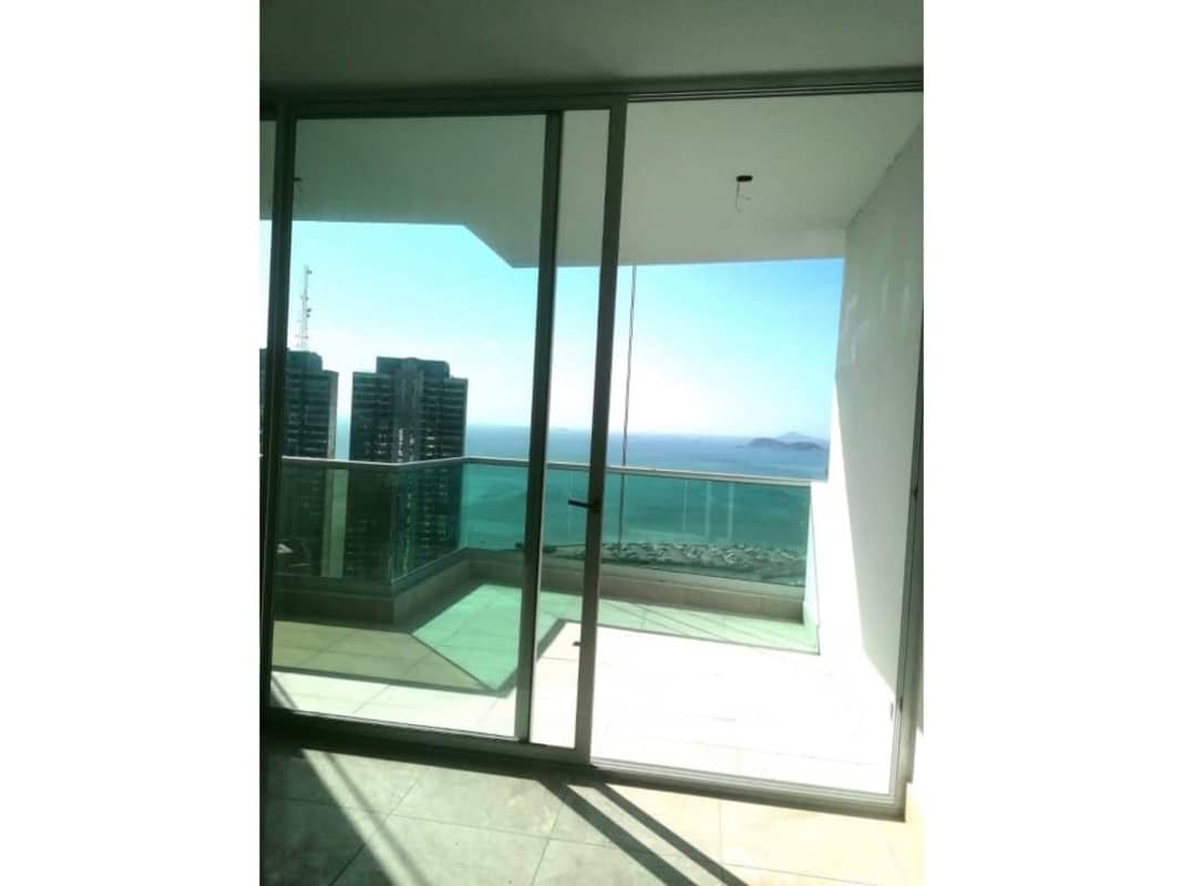 Spacious living room with glass doors opening to balcony with Pacific Ocean and skyline views in PH Costanera Panama City