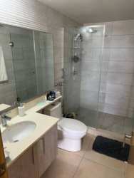 Modern bathroom tiled with glass shower in PH Parterre home, Panama Pacifico