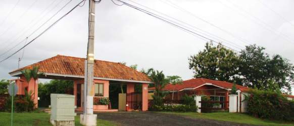 Exterior view of Mediterranean-style security entrance to PH La Colonia with tropical landscaping in Bejuco, Panama