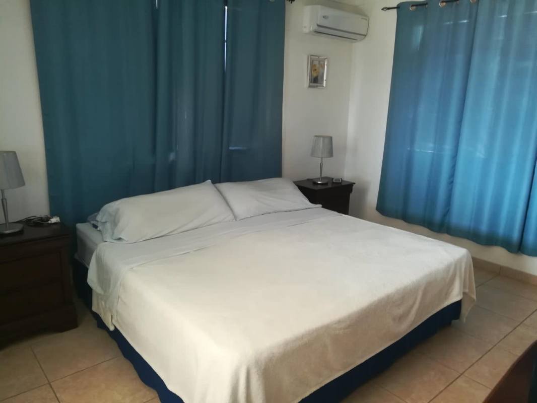 Bedroom with large bed, nightstands, split AC minimalist design in Brisas del Golf Panama