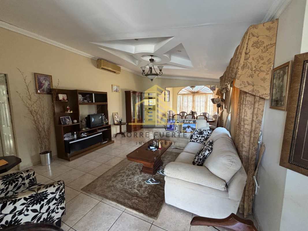Large living area with beige sectional sofa, ceramic floors and coffered ceiling in Brisas del Golf home