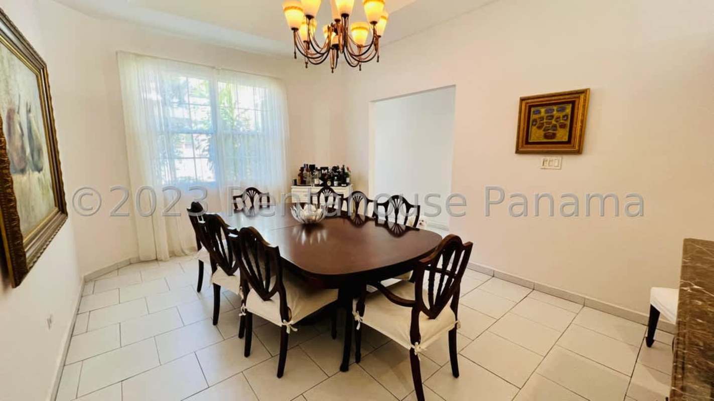 Traditional dining room with large wood table chandelier window overlooking garden in Altos del Golf Panama City