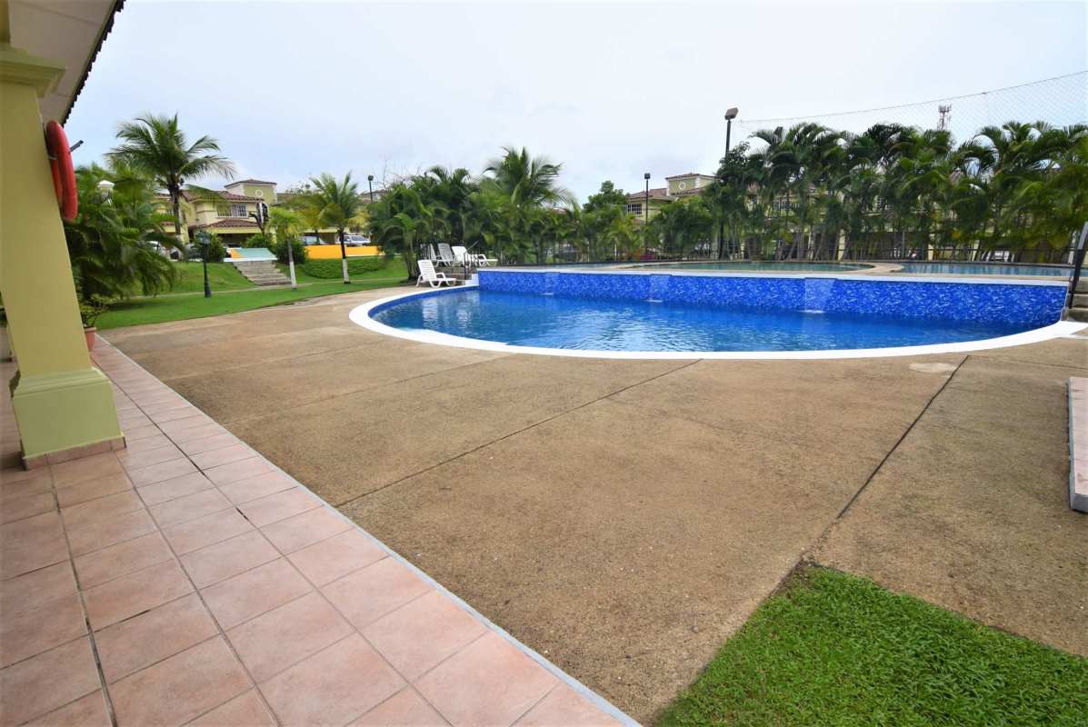 Large community swimming pool with palm trees and lounge area at Crystal Springs Panama City