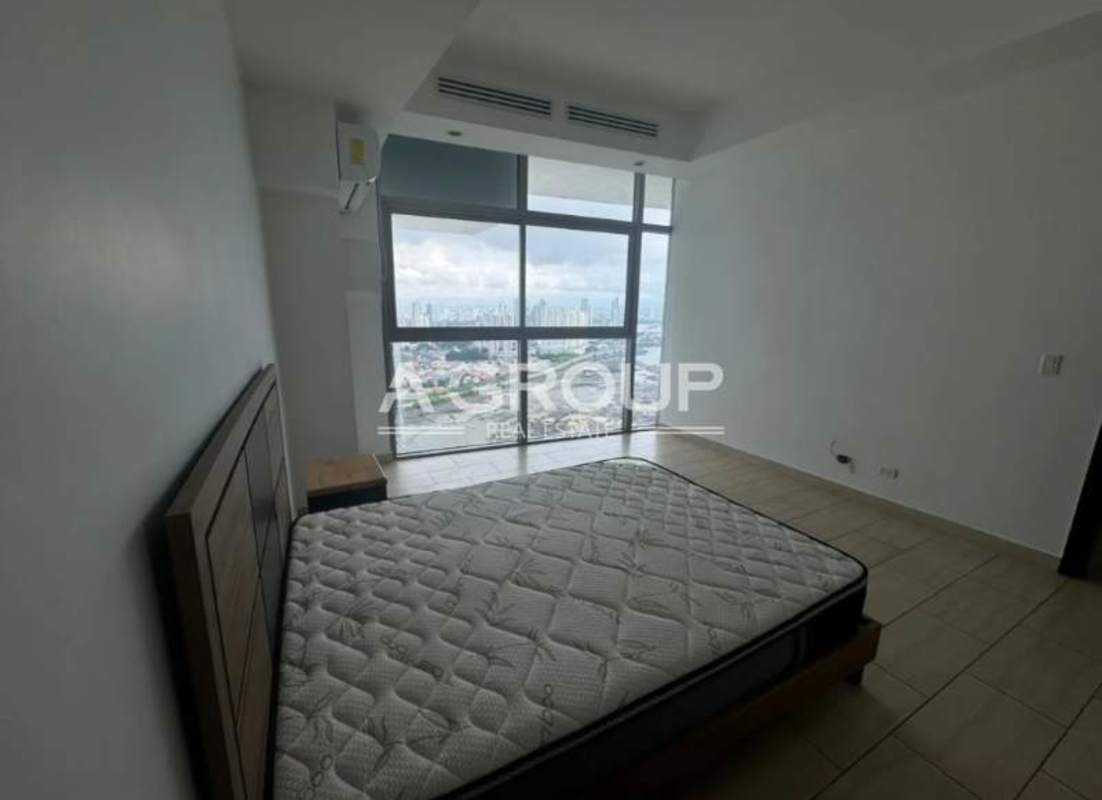 Bright bedroom with floor-to-ceiling windows overlooking Panama skyline in duplex apartment Grand Tower