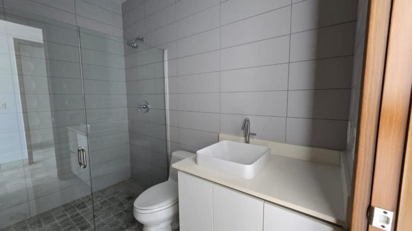 Modern bathroom with glass shower enclosure and marble details in Santa María golf condo