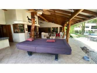 Spacious covered patio with pool table overlooking pool and garden in Panama home