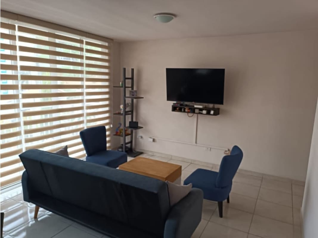Bright living room with navy blue sofa, large windows and tiled floor in PH Mallorca Park Los Andes