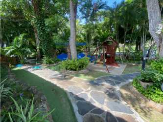 Family friendly yard with playground and tropical landscaping at Coronado Golf Beach Resort home