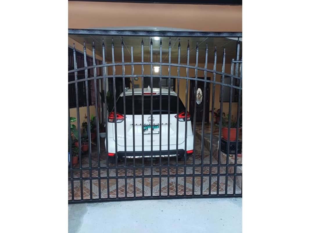 Front facade with clay tile roof, green metal gate, driveway Las Acacias Panama