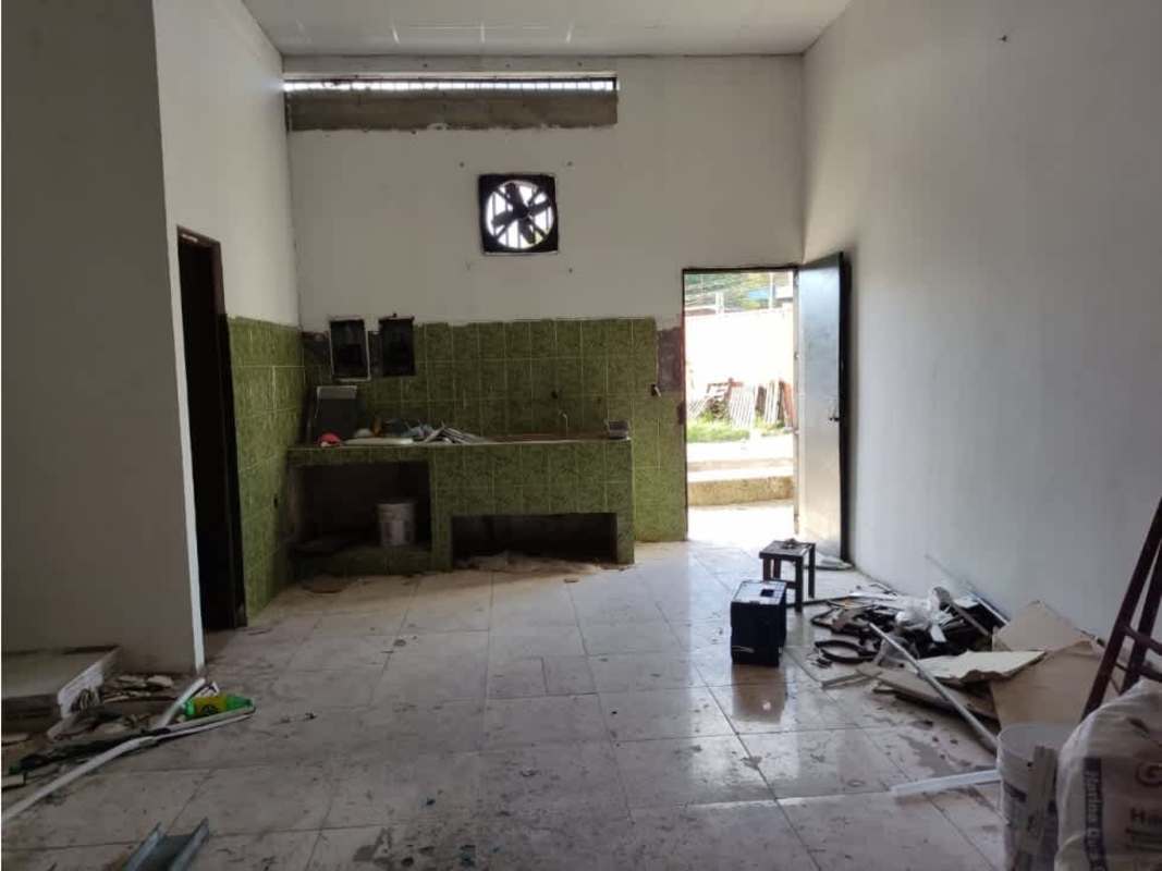 Unfinished kitchen area with green backsplash tiles, open door and debris in Ciudad Bolívar commercial space Panama