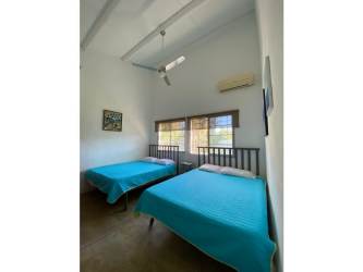 Bright bedroom in Santa Clara with ceiling fan, large window, twin beds and garden view