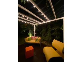 Santa Clara Beach house patio with pergola, string lights, and lounge furniture at night