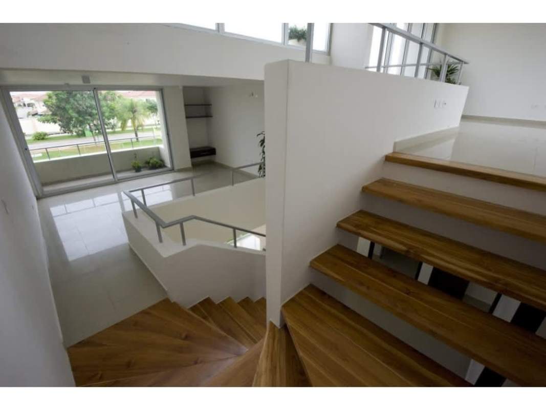 Modern townhouse interior with floating wood staircase, large sliding doors and garden view at Costa Sur Village Panama