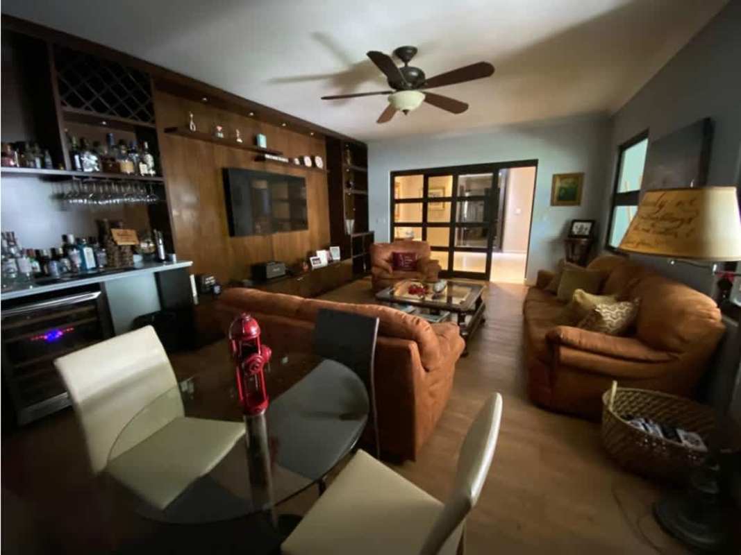 Living room with wooden built-in shelves, leather sofas, bar area and large windows Costa del Este Panama