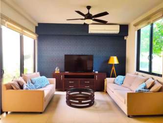 Bright living room area with sofas, accent wall, large windows and ceiling fan in home Panama Pacifico