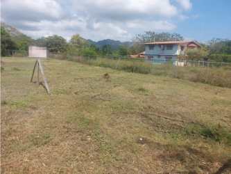 Large green lot with fence partial mountain view behind residential homes Malibú Nueva Gorgona