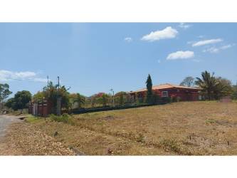 Grass vacant lot along gravel road near a red house in Punta Barco Coronado Panama