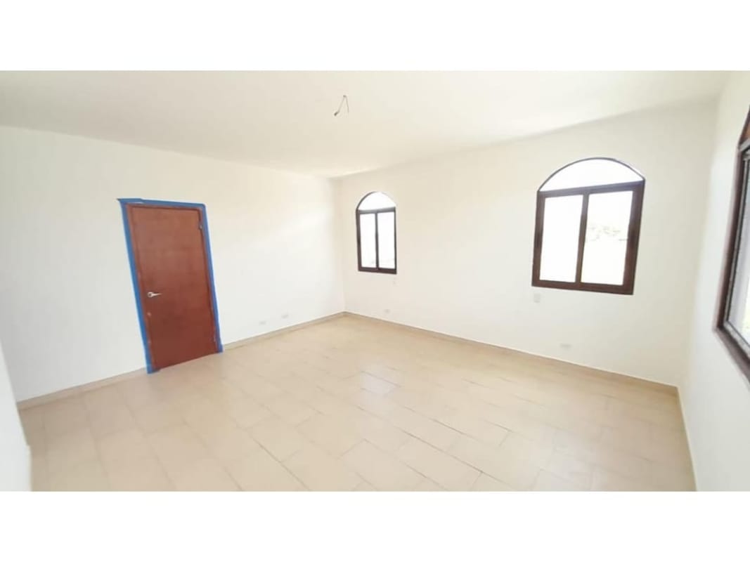 Two-story painted house with tiled roof, arched garage and lawn in El Doral Costa Sur Panama