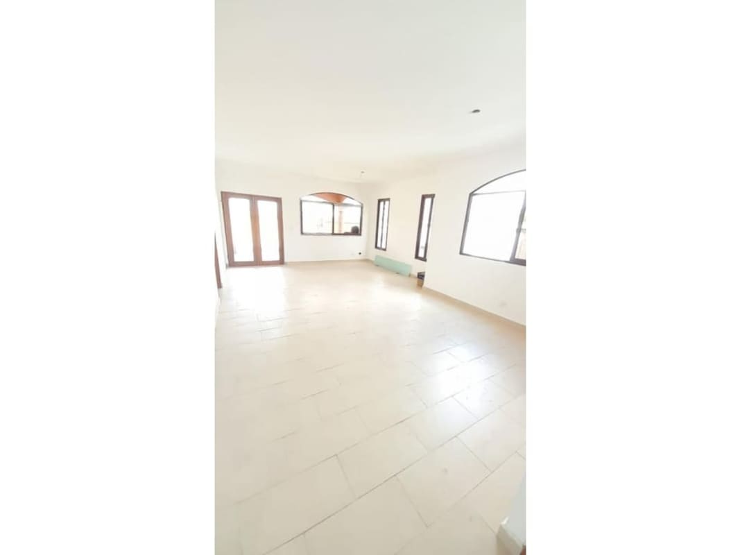 Modern empty bedroom with light tile floors and arched windows in Costa Sur Panama