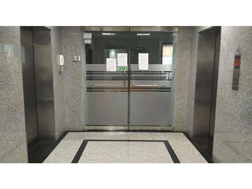 Commercial building elevator lobby with two elevators and frosted doors in Banco General Tower Calle 50