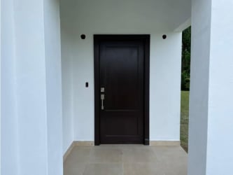 Front entrance with dark wood door and white walls new home Hacienda Pacifica Panama