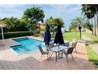 Outdoor pool with patio furniture, umbrellas, tropical landscaping at PH Playa Blanca Panama