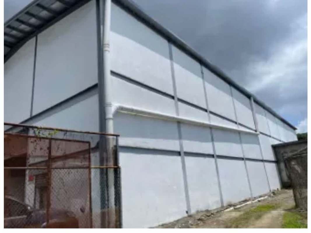 Exterior front of tall industrial warehouse with metal roofing and concrete pavement