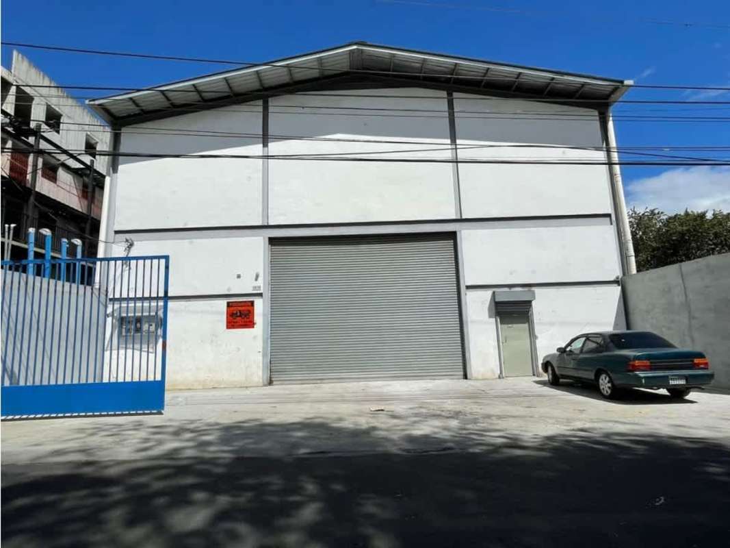 Wide exterior view of warehouse with fenced parking and rolling door in Rio Abajo