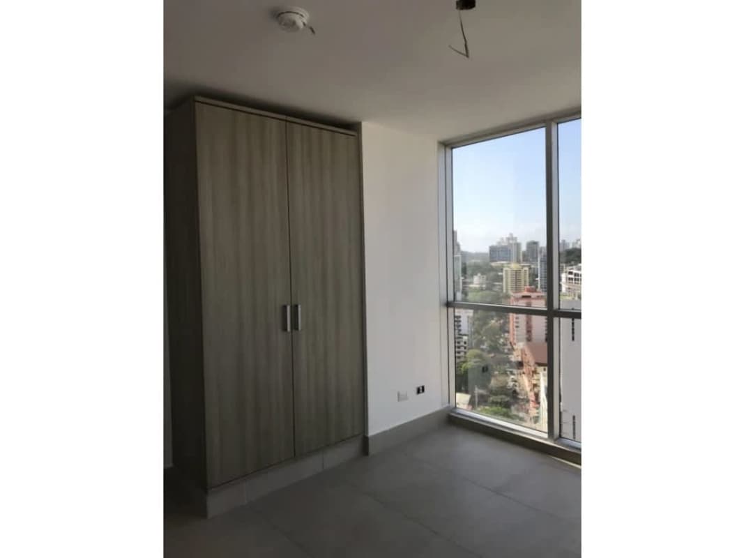 Modern bedroom with built-in wardrobe and large window offering city skyline views in PH Park City Obarrio Panama