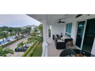 Bright dining room with glass table, pendant lights, terrace view in Bijao Beachfront condo Panama