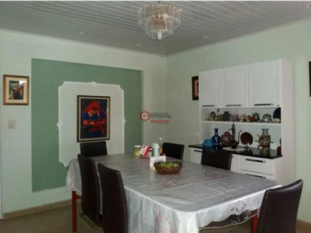 Dining room with chandelier decor, white cabinet and wall art in Panama City house
