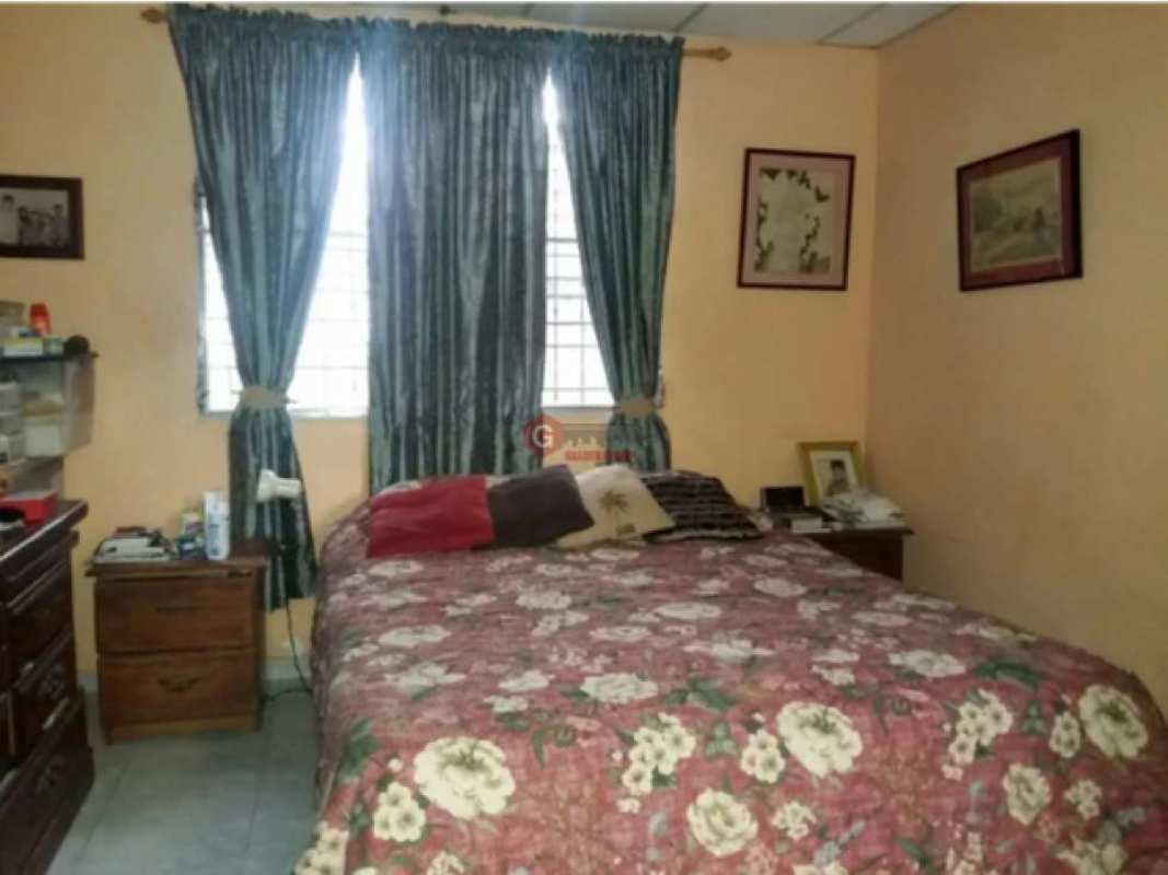 Bedroom with large windows and floral bedspread in Villa de las Fuentes house Panama City