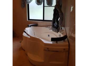 Modern bathroom with jacuzzi tub large window sheer curtains in Valle Escondido Boquete home