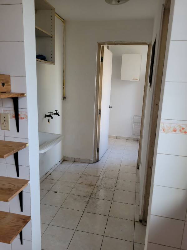 Kitchen with wood cabinets, louvered window, and tiled backsplash in Panama apartment