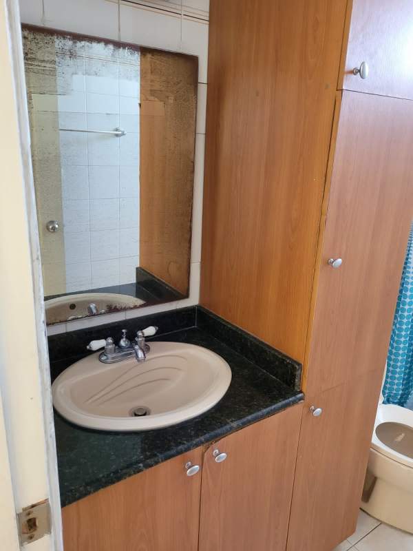 Bathroom vanity with granite counter, wooden cabinet, mirror in Villa de las Fuentes Panama apartment