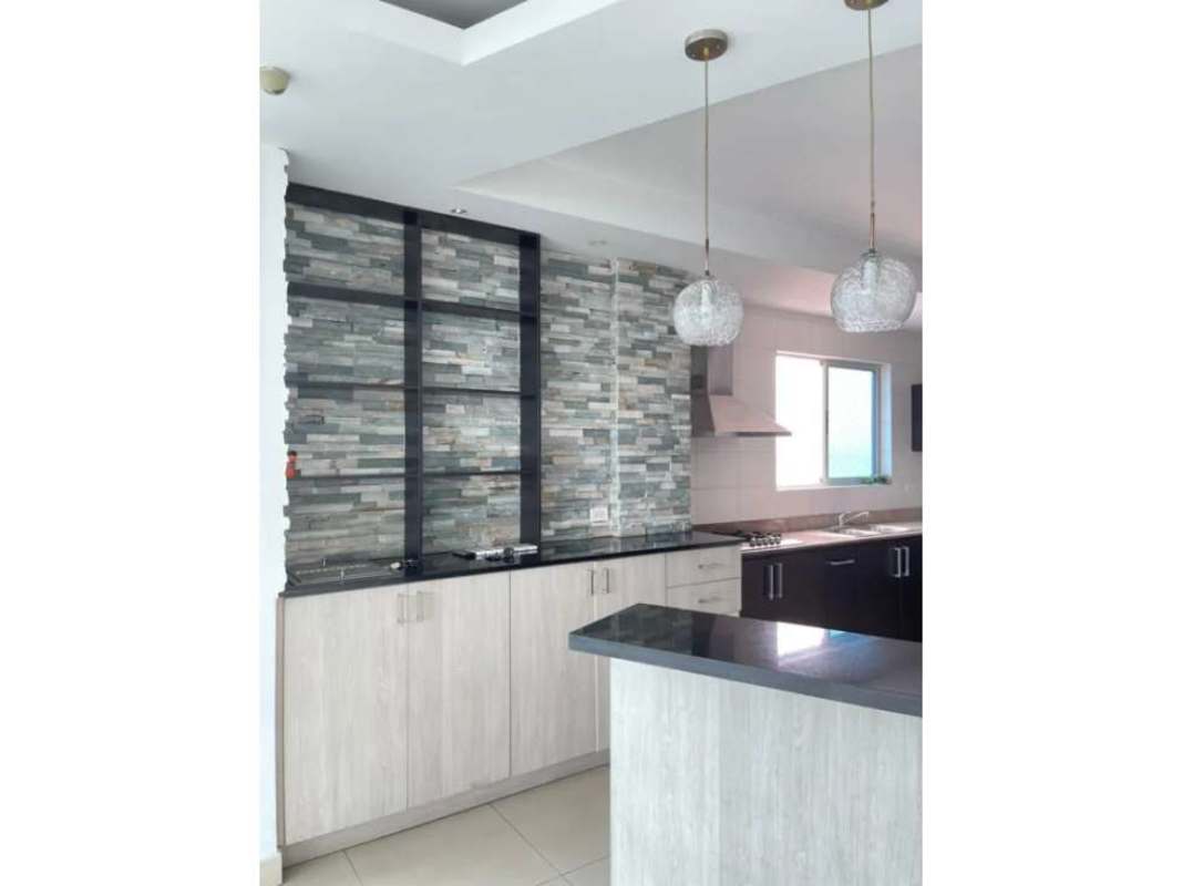 Open kitchen with granite counters and stone accent wall at The View Coco del Mar