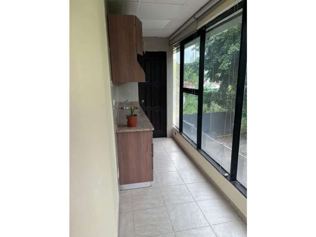 Small kitchenette with cabinets, sink, and window in commercial office Panama City