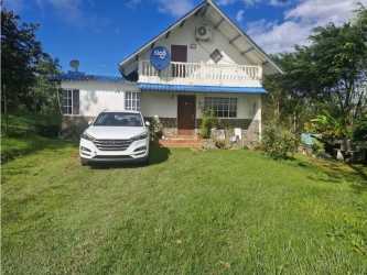Front elevation rustic mountain home with blue awning and balcony Cerro Azul Panama