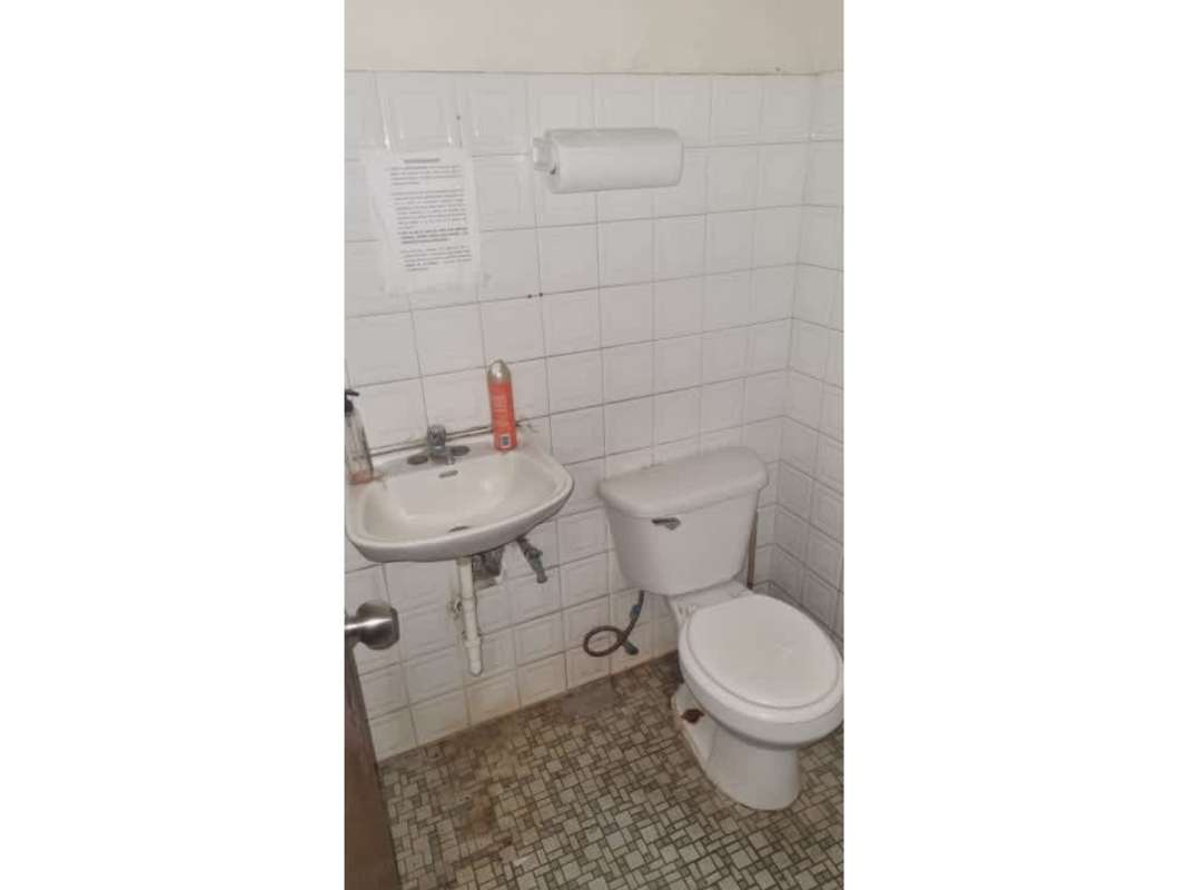 Simple bathroom with white wall tiles, sink, and toilet inside warehouse La Locería