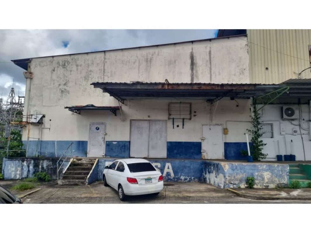Industrial warehouse exterior with canopy loading dock, white car parked, blue and white paint La Locería Panama