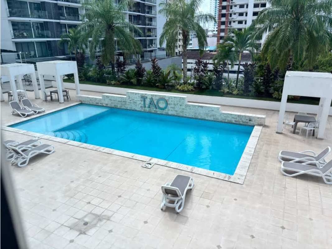 Infinity swimming pool with sun deck, lounge chairs and city view at PH Tao Tower San Francisco Panama