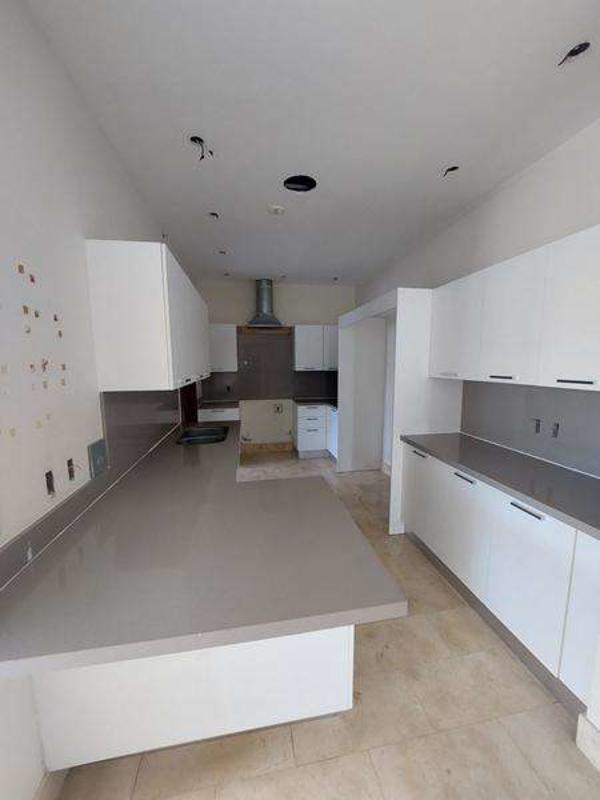 Spacious kitchen with island, white cabinets and marble flooring PH Greenview Residences Panama