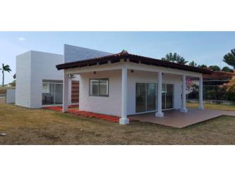 Single-story house exterior with red accent wall, tiled roof, covered carport beach home Panama