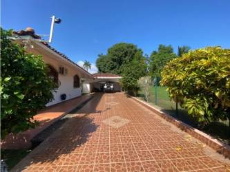 Front tiled driveway with garden and covered garage in Howard residential house Panama