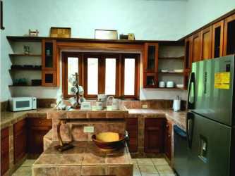 Rustic style kitchen with wood cabinets and tile counters in mountain villa Panama
