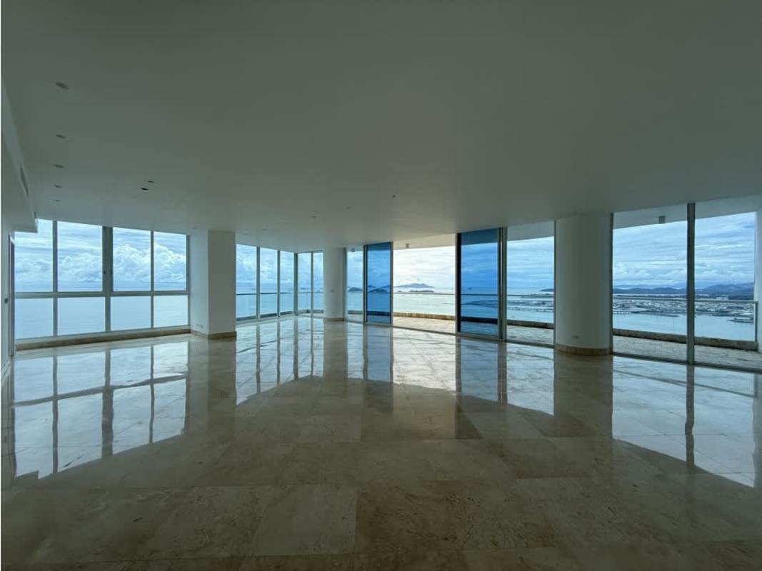 Grand living area with floor-to-ceiling windows and panoramic views of ocean and skyline in Punta Paitilla apartment.