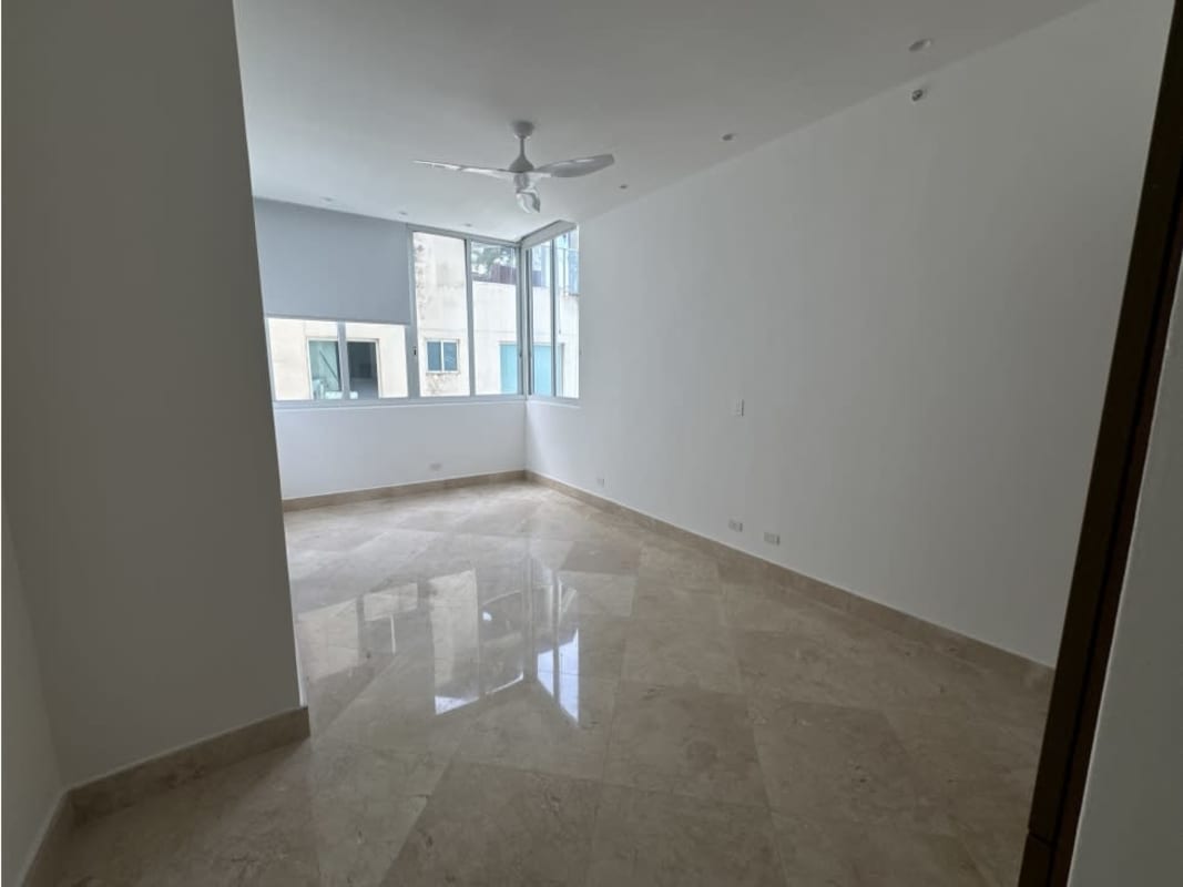 Spacious guest bedroom with ceiling fan, modern finishes, floor-to-ceiling windows overlooking bay.