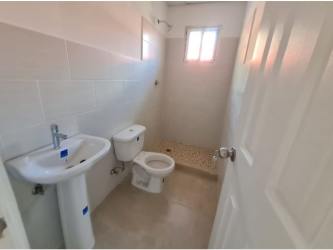 Minimalist bathroom with pedestal sink walk-in shower tile walls Altos Cerro Tigre house Panama