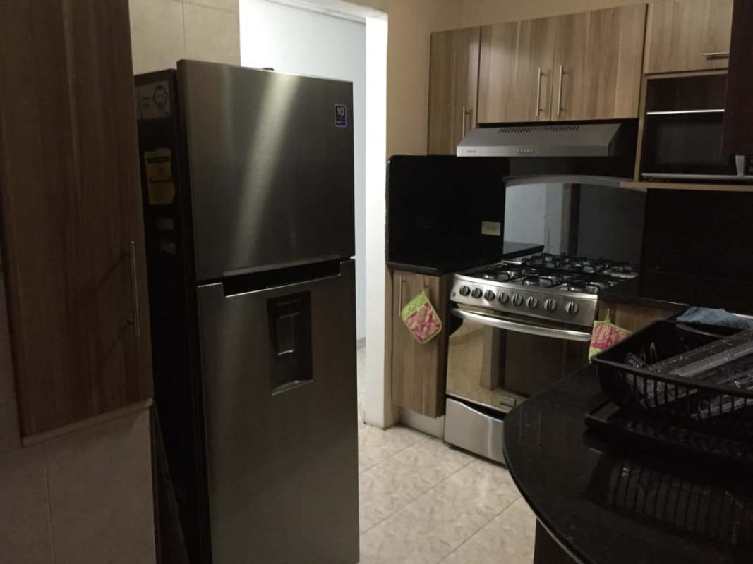 Modern kitchen with marble countertops stove refrigerator microwave wood cabinets Betania Panama City